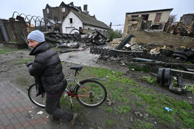 Un homme passe à côté d'un blindé russe et d'un bâtiment détruits à Gostomel, près de Kiev, le 22 avril 2022