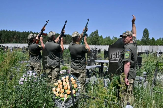 Des soldats ukrainiens honorent l'un des leurs par une salve lors de ses funérailles au cimetière de Boutcha, près de Kiev, le 20 juin 2022