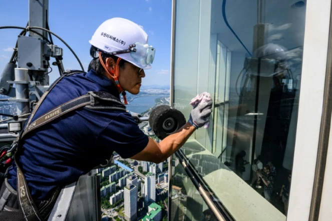 Seo Seung-ho nettoie les vitres du plus haut gratte-ciel de Séoul, le Lotte World Tower, depuis une "nacelle" suspendue par des câbles au 125e étage du bâtiment, le 4 juin 2024 à Séoul, en Corée du Sud