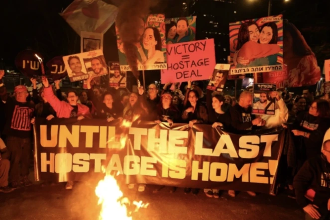 Des Israéliens tiennent des pancartes et allument des bougies lors d'une manifestation antigouvernementale appelant à agir pour obtenir la libération des otages israéliens à Gaza, devant le ministère de la Défense à Tel-Aviv le 18 janvier 2025 ( AFP / Jack GUEZ )