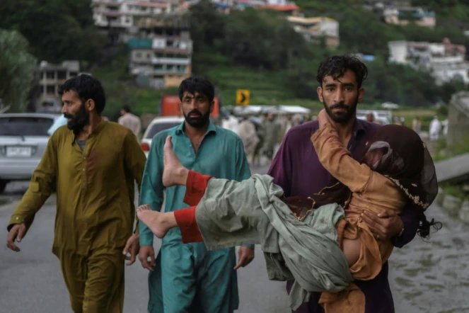 Un homme porte sa fille malade le long d'une route endommagée par les eaux de crue suite aux fortes pluies de mousson dans la région de Madian, dans la vallée de Swat, au nord du Pakistan, le 27 août 2022