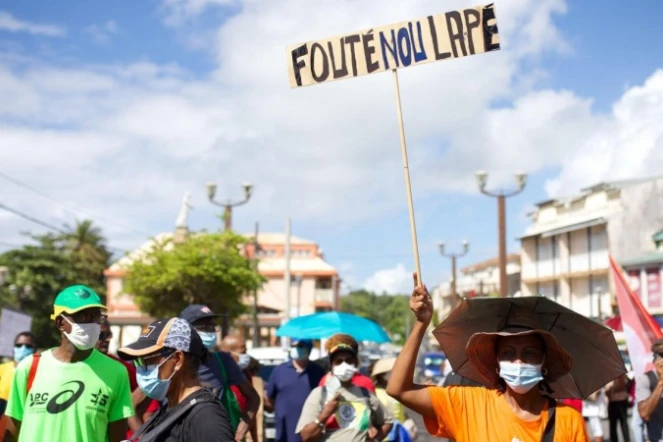 Militants de l'Union générale des travailleurs de Guadeloupe, faisant rouler des pneus pour installer un barrage à Perrin Les Abymes, en Guadeloupe, le 17 novembre 2021