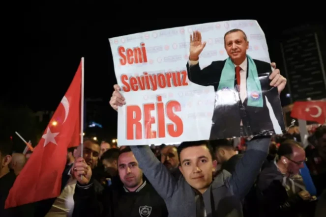 Un soutien du président turc sortant Tayyip Erdogan tient une affiche sur laquelle on peut lire "Nous t'aimons, Reis" pendant un rassemblement devant son parti, l'AKP, à l'issue du premier tour des élections générales à Ankara, le 15 mai 2023 ( AFP / Adem ALTAN )