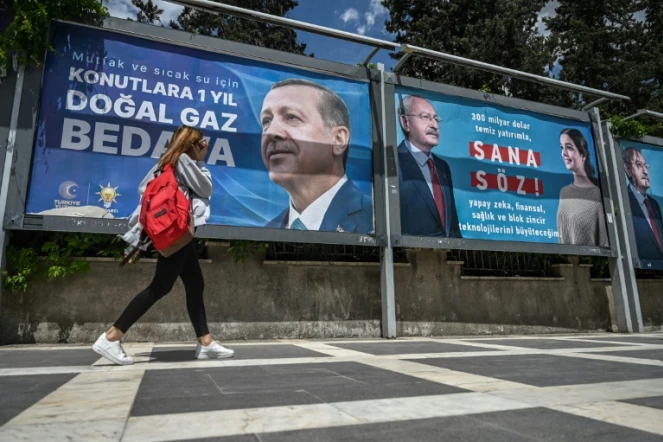 Une femme passe devant les affiches du président turc Recep Tayyip Erdogan (gauche) et de son principal adversaire à l'élection présidentielle Kemal Kiliçdaroglu (droite), le 28 avril 2023 à Sanliurfa, dans le sud-est de la Turquie