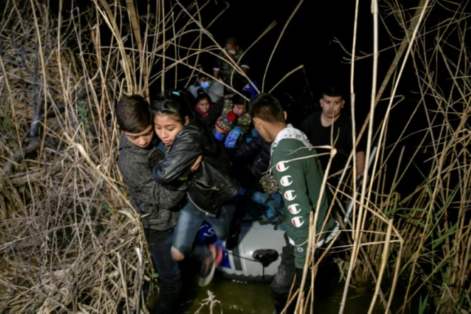 Un groupe de migrants venus du Honduras et du Guatemala débarque du bateau d'un passeur mexicain après avoir traversé le Rio Grance à Roma, au Texas, le 28 mars 2021.