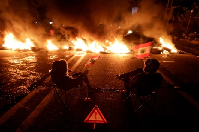 Des manifestants libanais devant des pneus enflammés, sur une route allant de Beyrouth à Byblos, le 21 janvier 2020