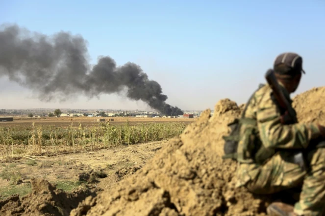 Un soldat syrien proturc regarde de la fumée noire s'élever au dessus de Ras al-Aïn, ville syrienne près de la frontière avec la Turquie, le 12 octobre 2019