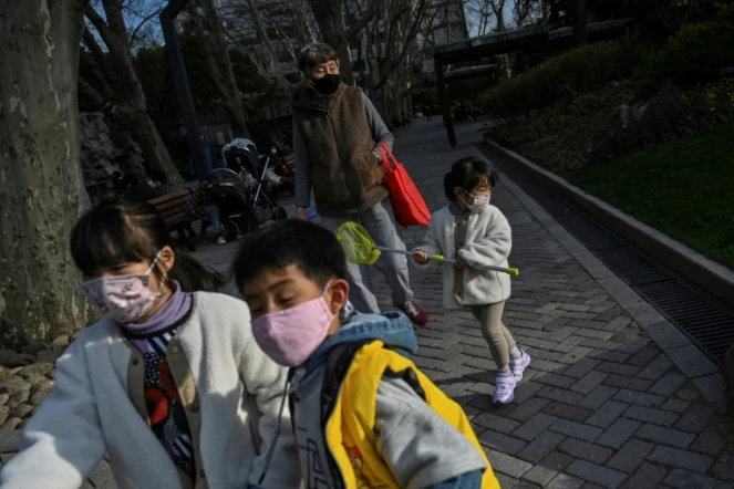 Des enfants, portant un masque de protection contre le coronavirus, jouent dans un parc à Shanghaï, le 17 mars 2020