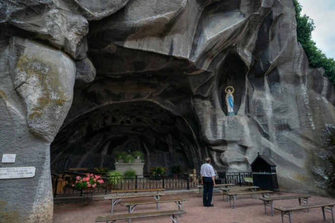 Un pèlerin prie devant la Grotte du Sanctuaire de Lourdes, le 14 août 2020 dans les Hautes-Pyrénées