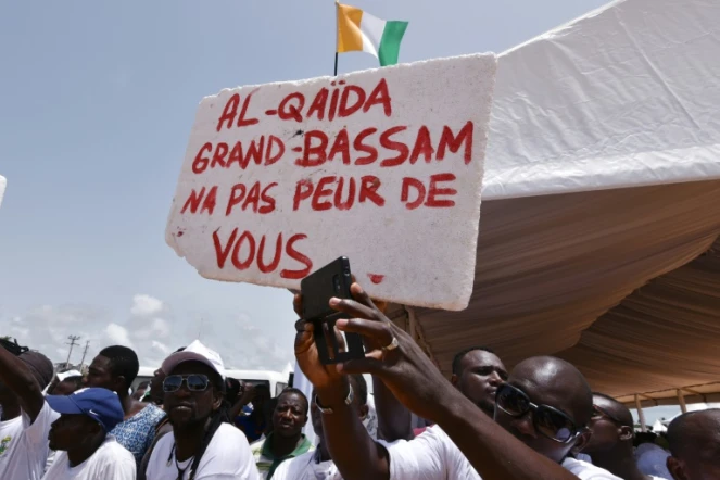 Des Ivoriens portent une pancarte "Al-Qaïda, Grand-Bassam n'a pas peur de toi", lors d'un hommage aux victimes de l'attaque jihadistes du 13 mars 2016 qui a fait 19 morts, le 20 mars 2016 à Grand-Bassam en Côte d'Ivoire