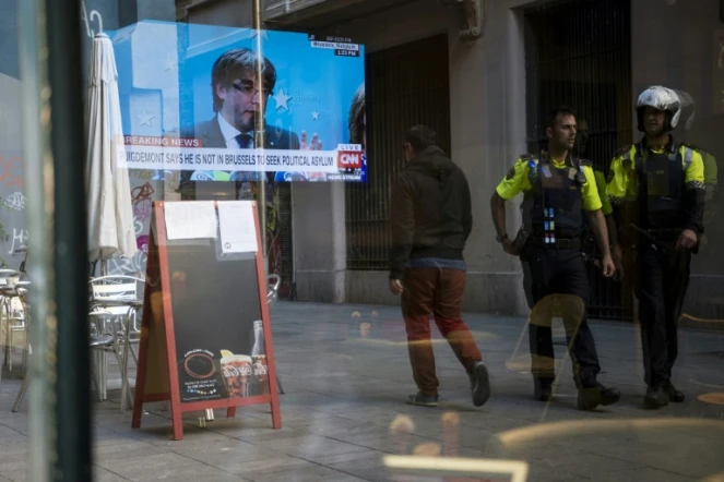 Des policiers catalans marchent devant un bar à Barcelone, dans lequel est diffusé une conférence de presse depuis Bruxelles du président catalan destitué par Madrid, Carles Puigdemont, le 31 octobre 2017