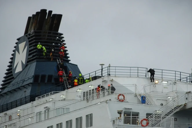 Des secouristes du Grimp (groupement de reconnaissance et d'intervention en milieux périlleux) tentent de faire descendre des migrants réfugiés en haut de la cheminée d'un ferry à Calais, le 3 mars 2019 