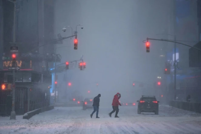 Des passants dans un Times Square sous la neige, à New York, le 29 janvier 2022