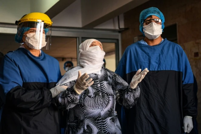 Des personnels soignants accompagnent Alye Gunduz (c), 93 ans, qui sort de l'hôpital après dix jours de traitement contre le Covid-19, le 10 avril 2020 à Istanbul, en Turquie