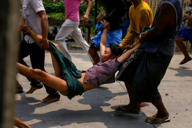 Transport d'un blessé lors des affrontements entre forces de l'ordre et manifestants dans la commune de Hlaing Tharyar, dans l'agglomération de Rangoun, le 14 mars 2021