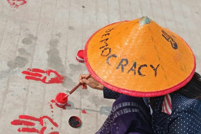 Photo prise et diffusée le 14 avril 2021 par une source anonyme via Facebook d'une manifestante à Shwebo dessinant sur le sol le salut à trois doigts avec de la peinture rouge en signe d'opposition au coup d'Etat militaire en Birmanie