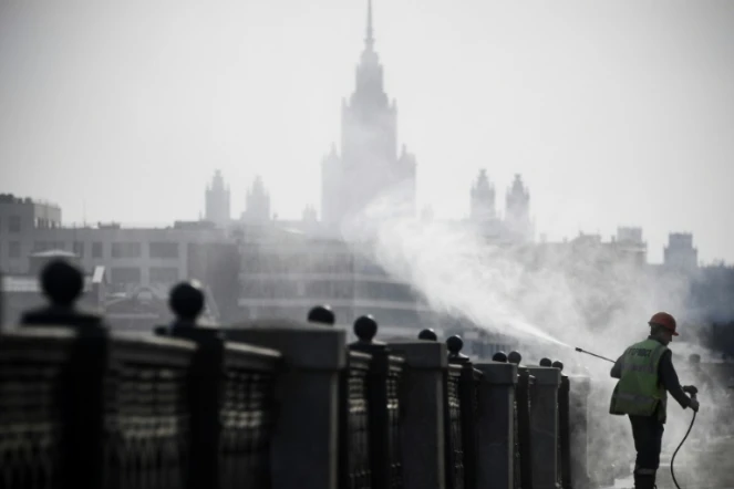 Un agent municipal désinfecte les bords des quais à Moscou, devant l'université d'Etat, le 28 mars 2020