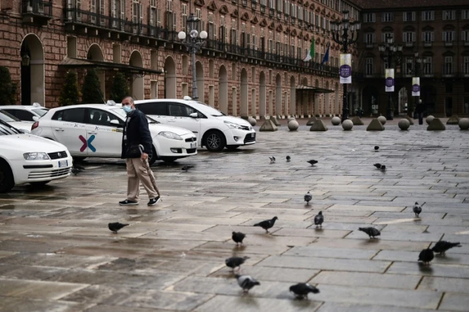 Un homme marche devant des taxis alignés sur la Piazza Castello à Turin, le 26 octobre 2020