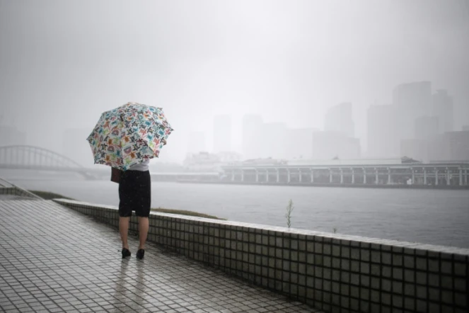 Une femme se protège de la pluie avec son parapluie à Tokyo le 28 juillet 2018 avant l'arrivée du typhon Jongdari