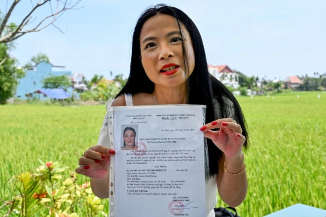 Odile Dussart, évacuée de Saïgon alors qu'elle n'était qu'un bébé de 11 mois, quelques semaines avant la fin de la guerre du Vietnam il y a 50 ans, montre son certificat de nationalité vietnamienne dans sa nouvelle maison à Hoi An, le 12 avril 2025