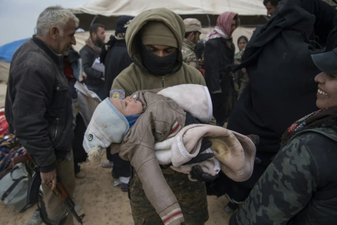 Un membre des Forces démocratiques syriennes (FDS) porte dans ses bras un enfant qui a fui avec sa famille le groupe Etat islamique à Baghouz, le 14 février 2019