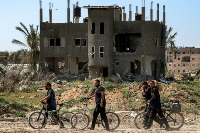 Des hommes longent un bâtiment détruit dans la ville de Khan Younès, dans la bande de Gaza, le 7 avril 2024 