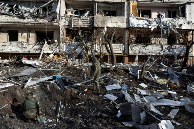 Des soldats ukrainiens dans les décombres d'un immeuble touché par une frappe, à Kiev le 15 mars 2022