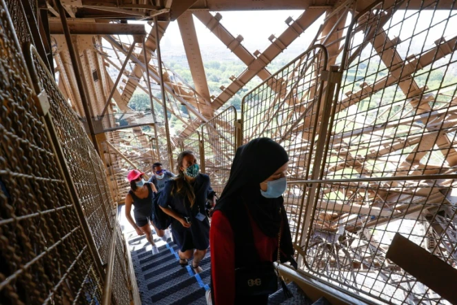 Des visiteurs portant des masques de protection montent les escaliers de la Tour Eiffel, le jour de sa réouverture, le 25 juin 2020 à Paris 