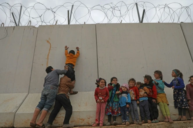 Des enfants déplacés syriens
tentent d'escalader le mur de la frontière turque, dans la province d'Idleb, le 21 février 2020
