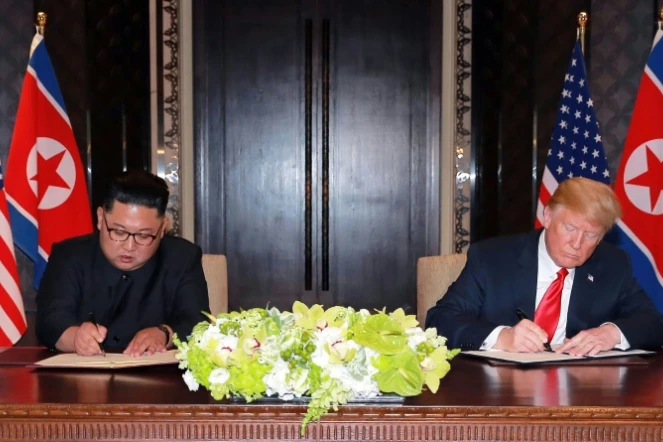 Le président américain Donald Trump et le dirigeant nord-coréen Kim Jong Un signent des documents lors de leur sommet à Singapour, sur une photographie prise le 12 juin 2018 et diffusée le lendemain par l'agence officielle nord-coréenne KCNA