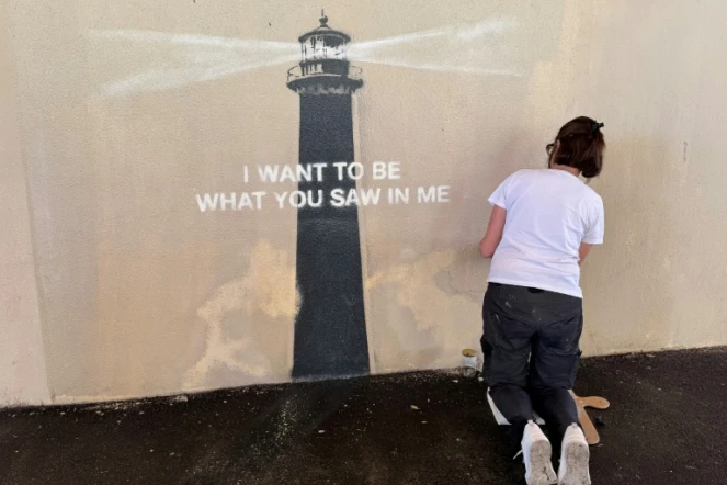 Agnès Perrone, peintre en décor du patrimoine, répare une œuvre d'art de l'artiste de rue Banksy représentant un phare sur la façade d'un bâtiment, après qu'elle a été vandalisée pendant la nuit à Marseille, le 1er juin 2025