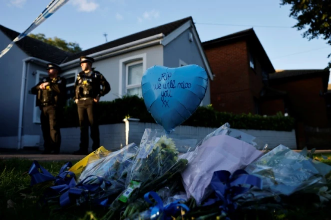 Des hommages sont placés près du lieu de l'aggression à l'arme blanche, tandis que des officiers de police montent la garde près de l'église méthodiste de Belfairs à Leigh-on-Sea, dans le sud-est de l'Angleterre, le 15 octobre 2021