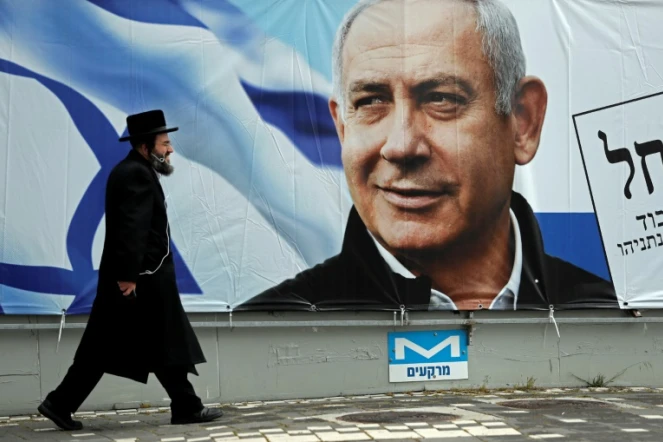 Un orthodoxe juif marche devant une affiche électorale du Premier ministre israélien Benjamin Netanyahu, le 1er avril 2019 à Jérusalem