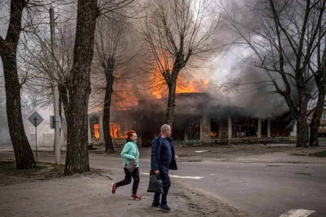 Des habitants courent dans une rue  de Seveodonetsk après un bombardement russe qui a touché une maison en flammes, le 6 avril 2022 dans la région du Donbass, dans l'est de l'Ukraine