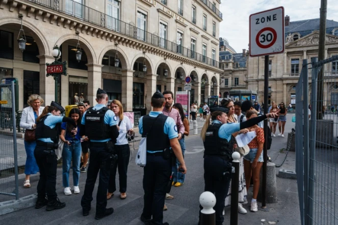 Des gendarmes vérifient les QR codes des piétons et leurs bagages à un point de contrôle près du musée du Louvre, le 18 juillet 2024 à Paris