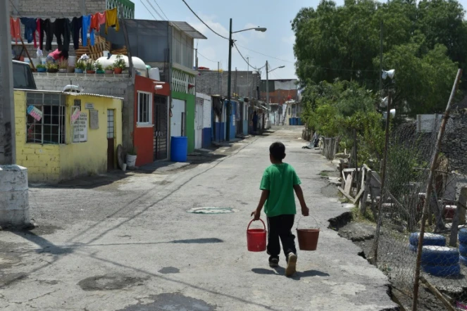 Un garçon porte de l'eau potable chez lui dans le quartier d'Iztapalapa, à Mexico, le 19 avril 2017