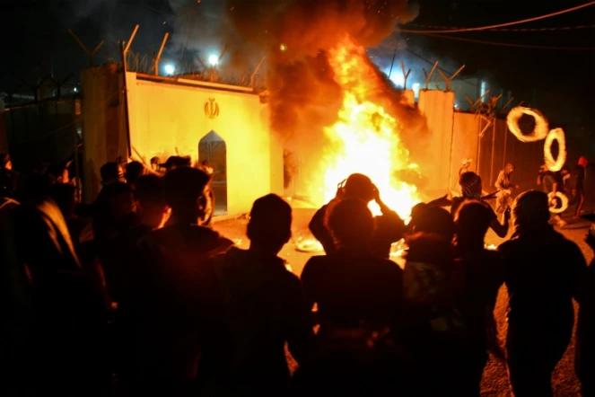 Des manifestants irakiens se rassemblent devant le consulat iranien dans la ville sainte chiite de Najaf, dans le sud de l'Irak, le 27 novembre 2019 alors que les flammes commencent à consumer le bâtiment