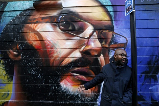 L'artiste britanno-ghanéen Neequaye Dreph Dsane se tient devant l'une de ses oeuvres à Londres, un portrait de l'artiste  britanno-marocain Hassan Hajjaj, le 15 janvier 2018