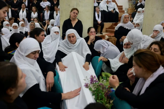 Des femmes druzes se recueillent près d'un cercueil lors des funérailles d'une personne tuée par un tir de roquette en provenance du Liban la veille, à Majdal Shams sur le plateau du Golan annexé par Israël, le 28 juillet 2024