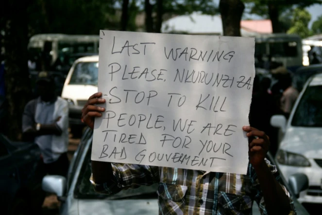 Une pancarte sur laquelle on peut lire "Dernier avertissement Nkurunziza, cessez de tuer des gens, nous en avons assez de votre mauvais gouvernement", brandie par un manifestant lors des funérailles d'un journaliste à Bujumbura le 20 octobre 2015