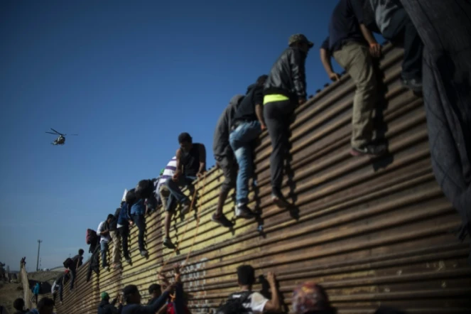 Des migrants centraméricains grimpent sur la barrière métallique marquant la frontière entre le Mexique et les Etats-Unis à Tijuana, le 25 novembre 2018