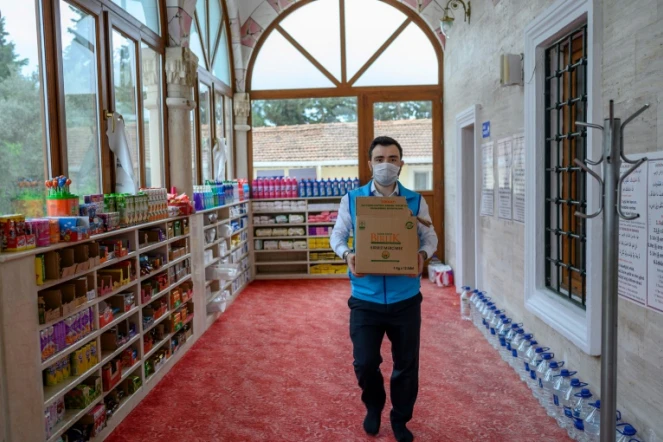 Abdulsamet Cakir, imam de la mosquée Dedeman à Istanbul, porte des cartons de vivres le 21 avril 2020 dans l'entrée de la mosquée