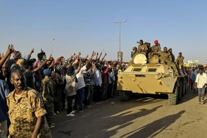 Des manifestants soudanais font le signe de la victoire en direction de militaires de l'armée à Khartoum, le 7 avril 2019