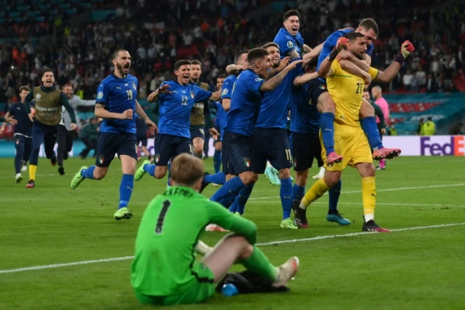Le gardien de but italien Gianluigi Donnarumma, félicité par ses coéquipiers, après avoir repoussé le pénalty du milieu de terrain anglais Bukayo Saka, lors des tirs au but, offrant la victoire (1-1, 3-2 t.a.b.) à la Squadra Azurra, le 11 juillet 2021 au stade de Wembley à Londres