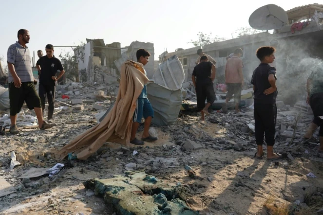 Des Palestiniens inspectent les décombres d'un bâtiment après un bombardement israélien à Khan Younès, dans le sud de la bande de Gaza, le 27 août 2024