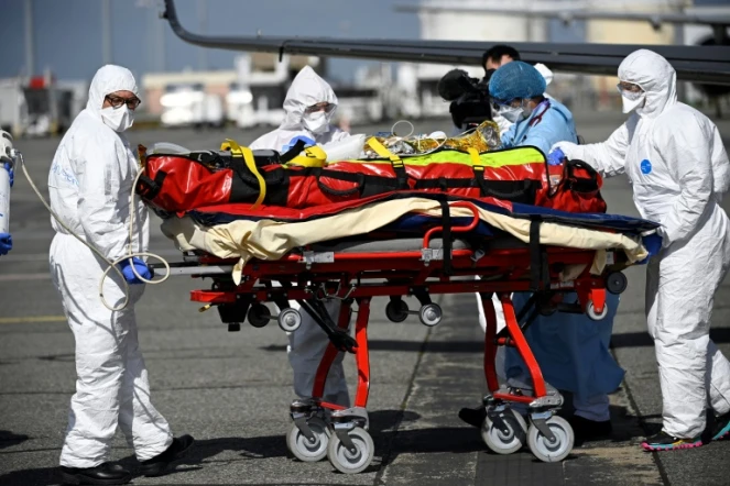 Le personnel médical transporte un patient infecté par le Covid-19 qui a été transféré de Nice, où les unités de soins intensifs sont surchargées, le 16 mars 2021 à Toulouse-Blagnac