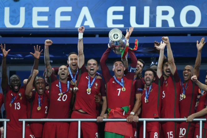 L'attaquant vedette du Portugal Cristiano Ronaldo (c) brandit le trophée entouré des ses équipiers après la victoire face à la France en finale de l'Euro au Stade de France, le 10 juillet 2016 