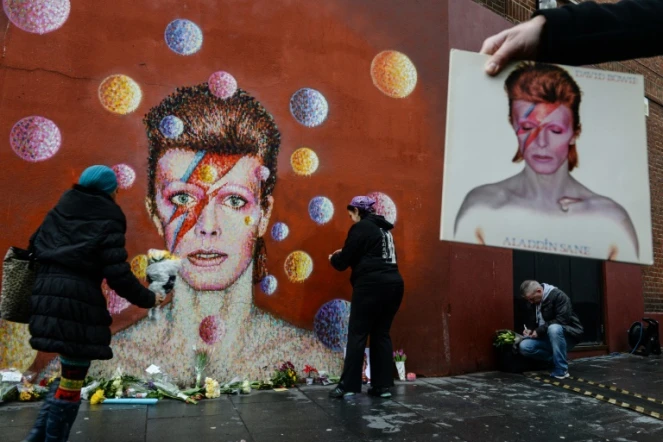 Des fans déposent des fleurs en hommage au chanteur David Bowie, après l'annonce de son décès, devant une fresque à son effigie, de l'artiste de rue australien James Cochran, dans le quartier de Brixton, à Londres, le 11 janvier 2016.