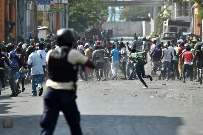 Un policier vise des manifestants avec une arme, lors de violents affrontements à Port-au-Prince, le 13 février 2019 en Haïti