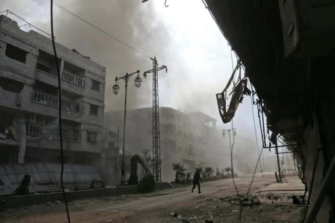 De la fumée et de la poussière s'élèvent d'une rue après des raids aériens du régime syrien sur la localité de Hammourié, dans le fief rebelle de la Ghouta orientale près de Damas, le 21 février 2018 